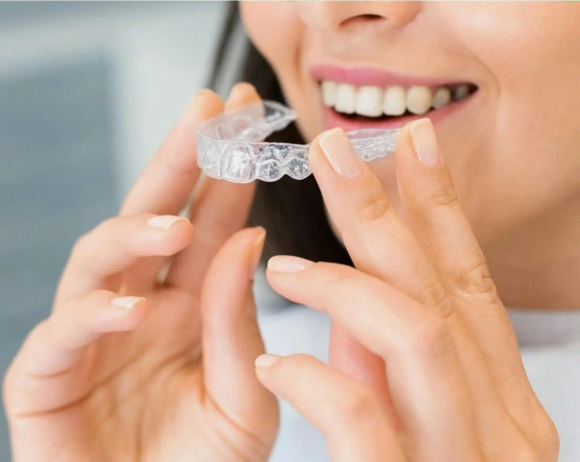 Nærbilde av en kvinnelig pasient som holder Invisalign-skinner foran munnen