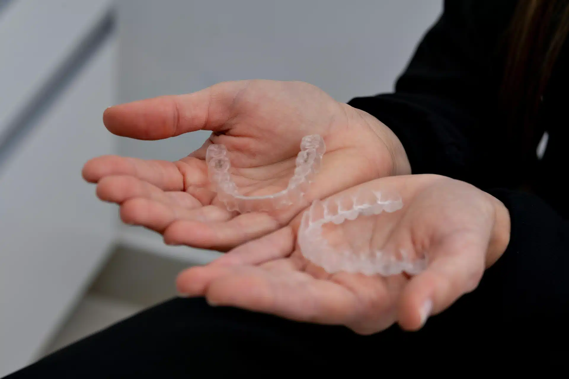 Nærbilde av Invisalign-skinner (usynlig tannregulering) i hendene på en pasient